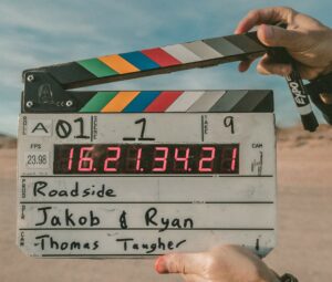 Person holding clapperboard with beach in the background