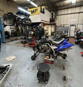 Photo of garage with cars and motorcycles being repaired